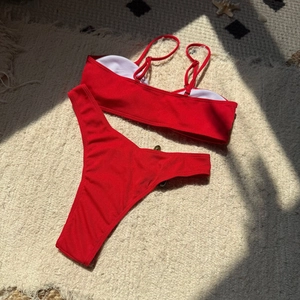 Flat lay of a red ribbed bikini set with adjustable straps on a soft plush background