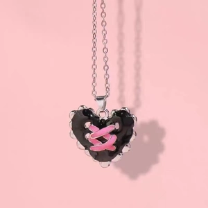 Y2K vintage black heart pendant necklace with pink cross ribbon on pink background