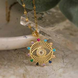 Gold plated evil eye sun pendant necklace with multicolored zircon stones on marble surface