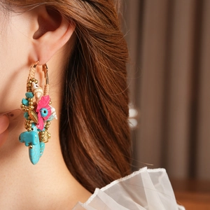 Detail of bohemian woven hoop earring with turquoise beads and pink fabric flowers