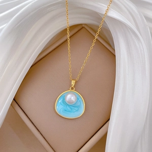 Collier en acier titane avec pendentif émail bleu marbré et perle dans un écrin