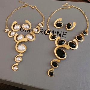 Detail of elegant gold oval necklaces and earrings with white and black enamel inlay