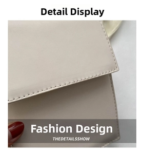 Close-up of double stitching detail and matte texture on beige leather crossbody bag