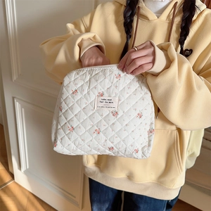 Detailed view of quilted floral makeup bag with classic red flower pattern and zipper