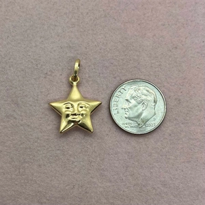 Detailed view of a gold star face pendant next to a coin for size reference
