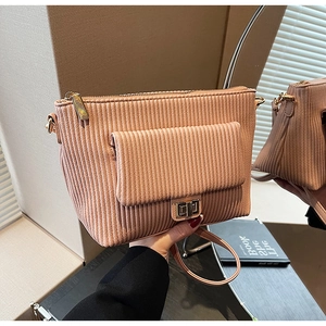 Detail of pink pleated crossbody bag featuring metal turn-lock and vertical texture