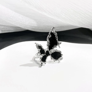 Detail of silver butterfly ring with black faceted stones and lava texture finish