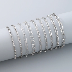 Detailed view of various silver stainless steel chain styles on a grey pedestal display