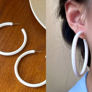 Detail of cream white matte hoop earrings showing resin material and on-model styling