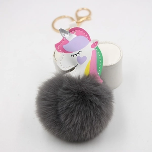Macro detail of a colorful unicorn PU leather piece and a grey fluffy faux fur pompom keychain