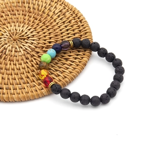 Detailed close-up of chakra volcanic stone bracelet on a brown woven texture coaster