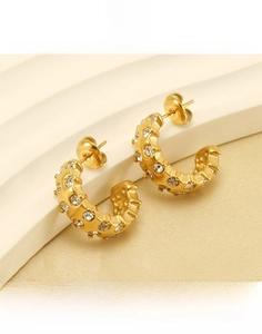 Macro shot of gold-plated C-shaped earrings with micro-set cubic zirconia on a silk base