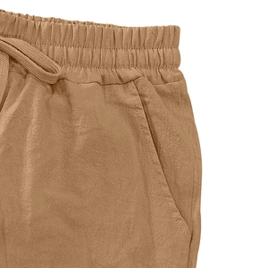 Detail of elastic drawstring waistband and textured linen fabric on brown casual shorts