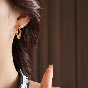 Close-up of gold hollow clover earrings showing polished interlocking metal hoops