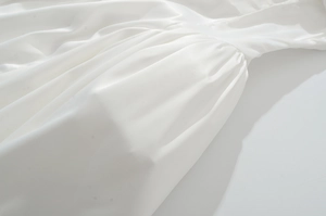 Primer plano de vestido de satén blanco con cintura plisada y textura de tela de seda