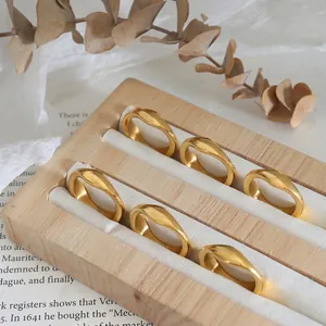 Minimalist wavy 18K gold plated titanium steel rings for women on wooden tray
