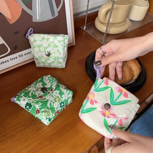 Close-up of mini floral canvas pouches with retro metal snaps and purple wrist straps