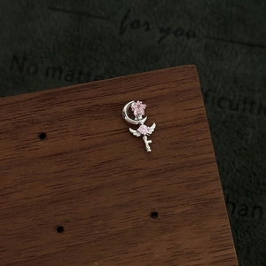 Macro shot of silver magic wand earring with pink zircons on a dark wood stand