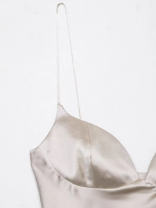 Detailed close-up of champagne satin fabric and delicate spaghetti straps on camisole