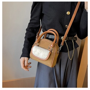 Detail of plush brown shoulder bag with white faux shearling front pocket and dual handles
