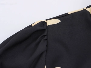 Detailed macro view of the shoulder seam with pleat design on a black printed dress