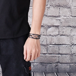 Dettaglio del bracciale multistrato in pelle nera con simbolo dell'infinito sul polso
