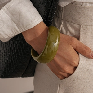 Close-up of olive green irregular acrylic chunky bangle on model with linen outfit