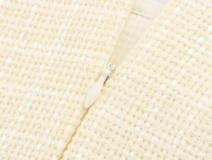 Détail de la texture en tweed et zip invisible sur une robe courte crème