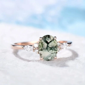 Macro shot of rose gold ring with marquise-cut accents and oval green natural stone