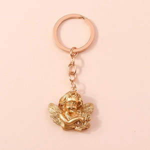 Detail of vintage gold angel keychain with harp on a soft pink background