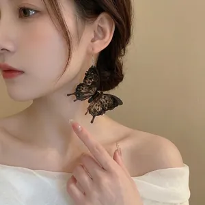 Vintage style black butterfly drop earrings featuring realistic translucent wings on a model