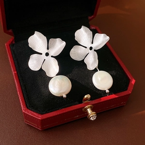 Detailed view of silver flower earrings with white freshwater pearls in a red jewelry box