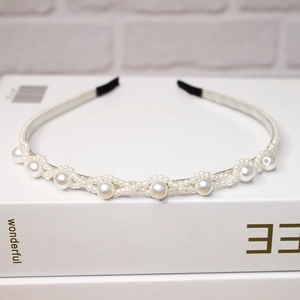 Dettaglio elegante cerchietto con perle bianco crema e motivo a onde intrecciate