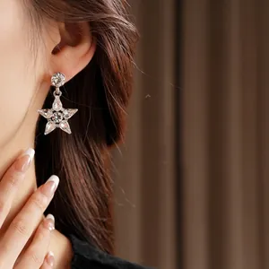 Silver star pendant earrings with sparkling diamonds on a model wearing them