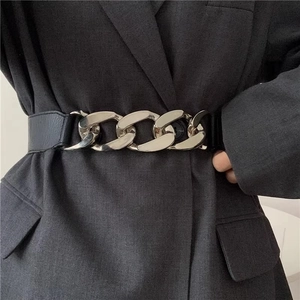 Detail of silver heavy chain belt with elastic black band on a grey suit jacket