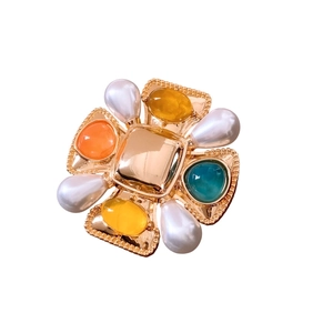 Vintage gold cross brooch with colorful gemstones and pearls on white background
