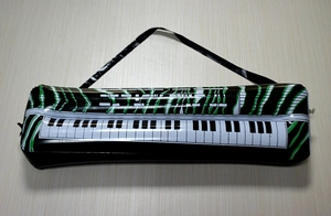 Close-up of inflatable keyboard piano toy with white keys and black strap on wooden surface
