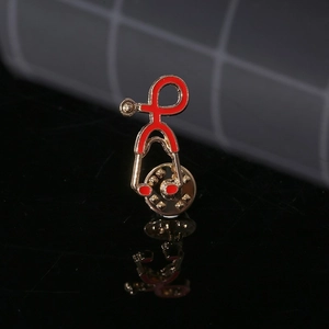 Creative gold stethoscope brooch with red enamel finish on a black reflective surface