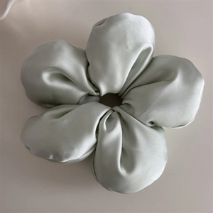 Close-up of light green silk scrunchie with a soft cloud-like texture and glossy finish