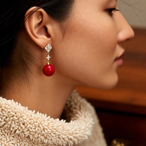 Detail of red round pearl drop earrings with 18K gold plated zircon flower studs on model