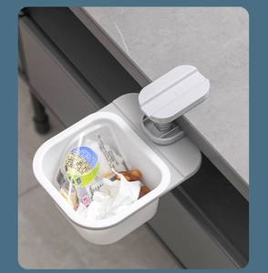 Close-up of a white plastic hanging trash bin clipped onto a countertop for kitchen use
