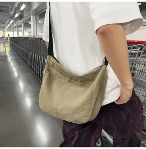 Detail view of khaki large capacity crossbody bag with adjustable black strap and outer pocket