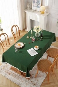Dark green cotton tablecloth with white lace edges on a wooden table in a retro French setting
