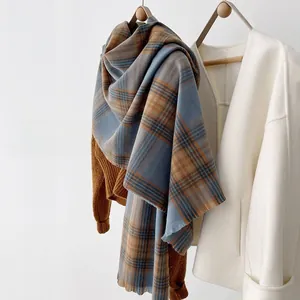 Detail of soft plaid scarf with tassels, featuring classic blue and brown woven texture