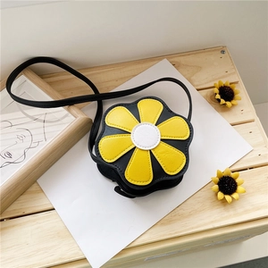 Top-down view of black floral PU leather crossbody bag with yellow petals on wood surface