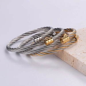Detailed macro of three-tone stainless steel cable wire bangles on a stone base