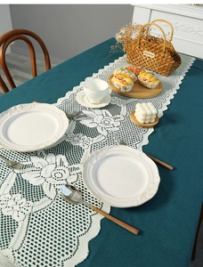 Detailed lace table runner with floral patterns displayed on a rustic blue dining table