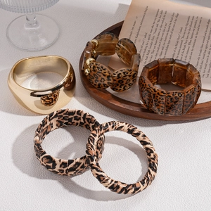 Retro leopard print acrylic and metal bangles set in brown gold tones on a rustic background
