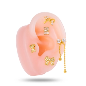 Five-piece gold bow stud earring set with cubic zirconia on a realistic ear model