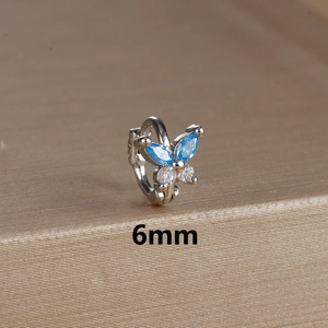 Macro detail of a 6mm silver butterfly huggie earring with blue marquise stones and S925 stamp
